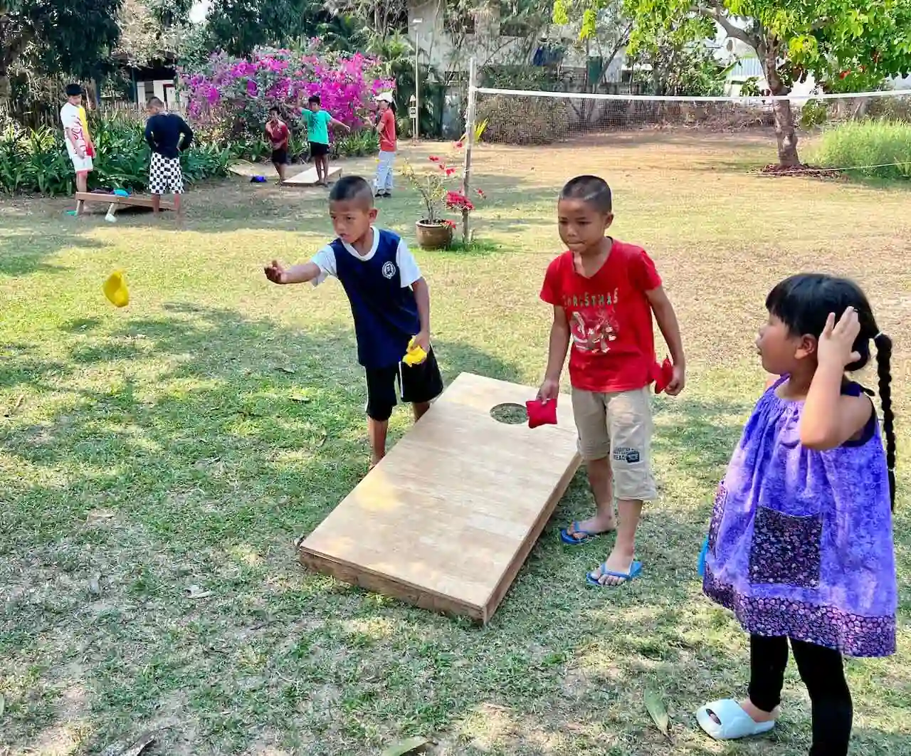 Kids playing cornhole on the grass at Camp 99