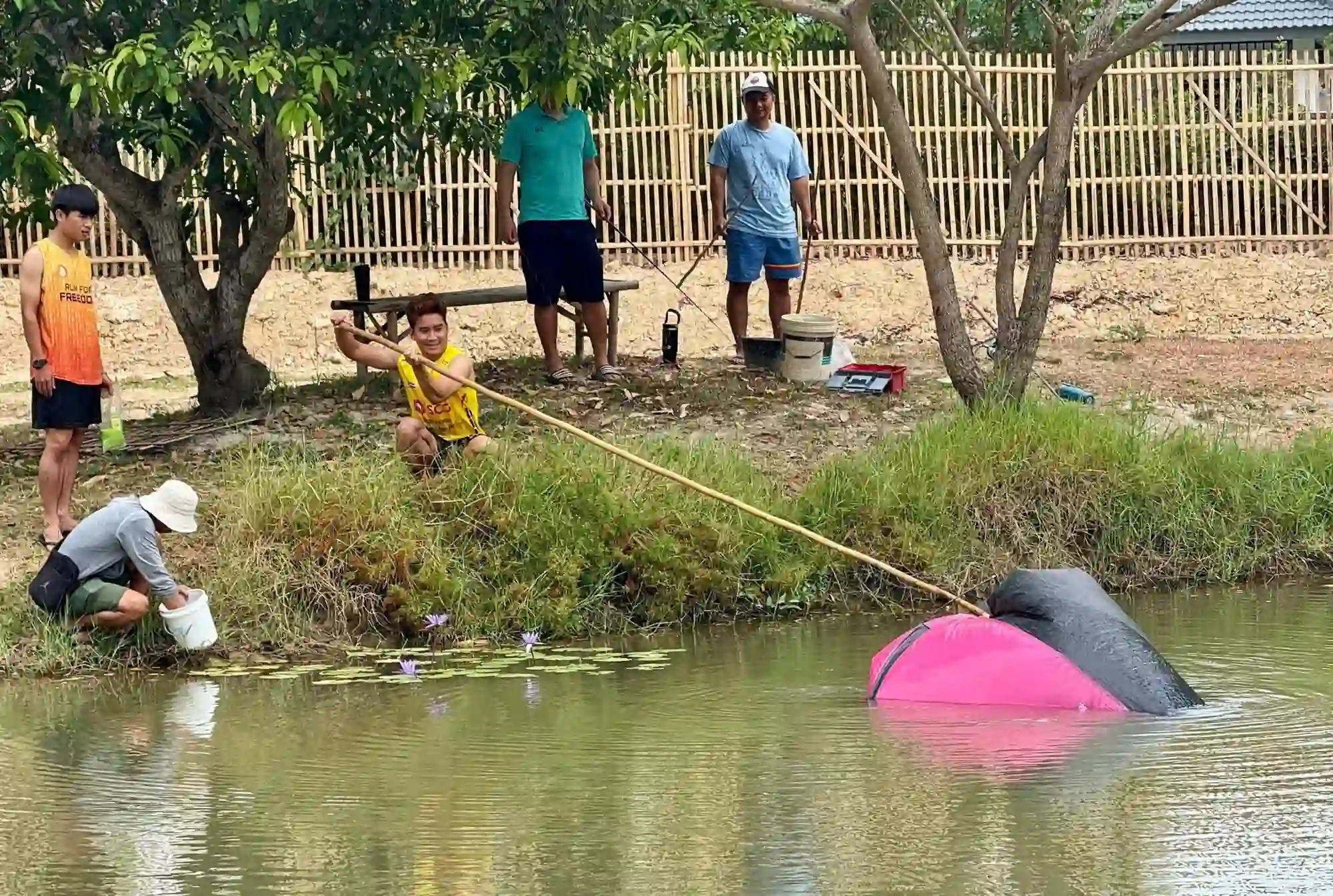 Fishing at the Camp 99 pond beside a bamboo fence