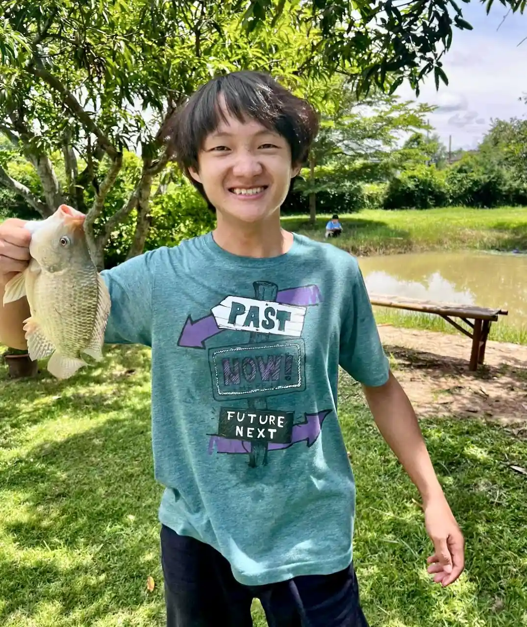 Smiling young man holding a tilapia at Camp 99