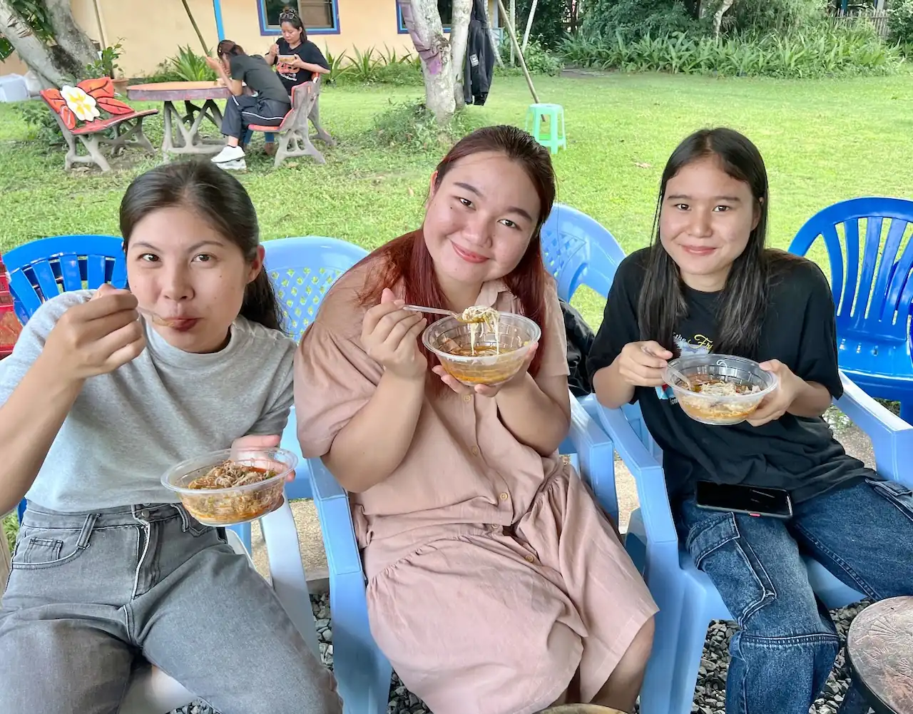 Three friends eating lunch outdoors at Camp 99