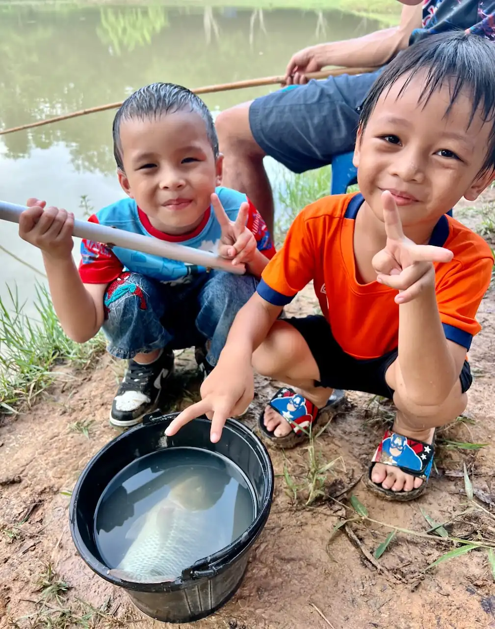 Two kids smiling over a bucket of fish at Camp 99