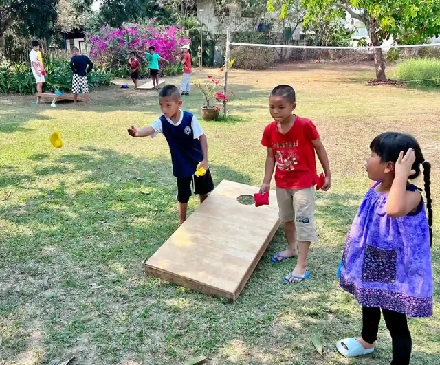 Kids playing cornhole on the grass